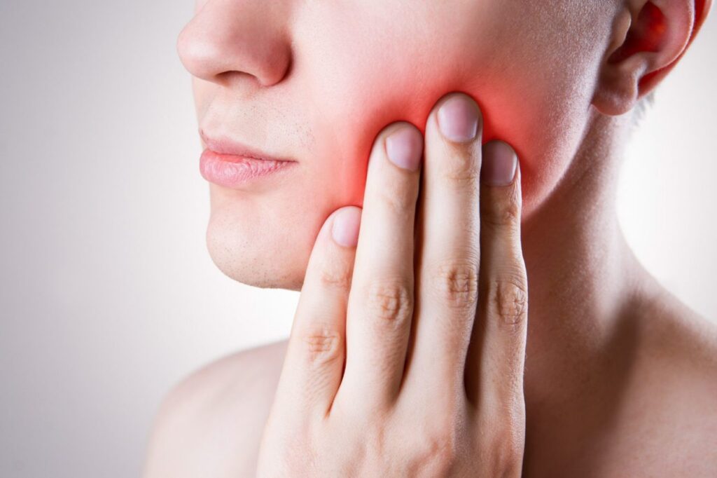 Man holds his jaw in pain from TMJ dentist in Indianapolis Indiana